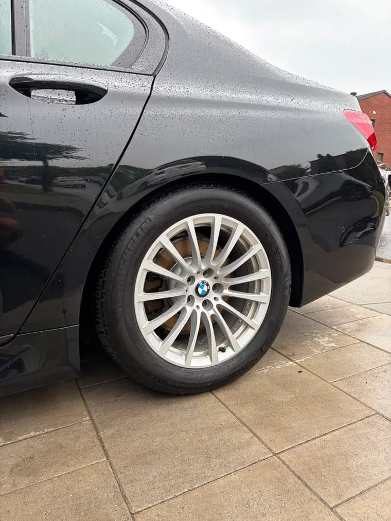 Water beading on the rear quarter of a freshly detailed black BMW 7 Series in Montreal