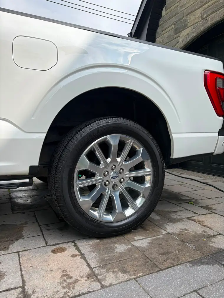 Polished wheel on a white Ford F-150 Limited after a wheel and tire detail